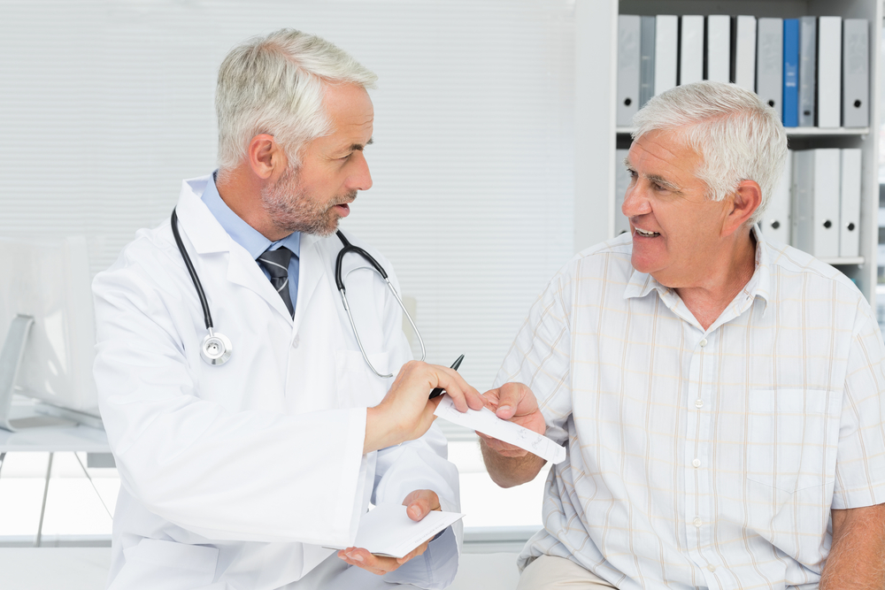 Male doctor giving a prescription to his senior patient at the medical office