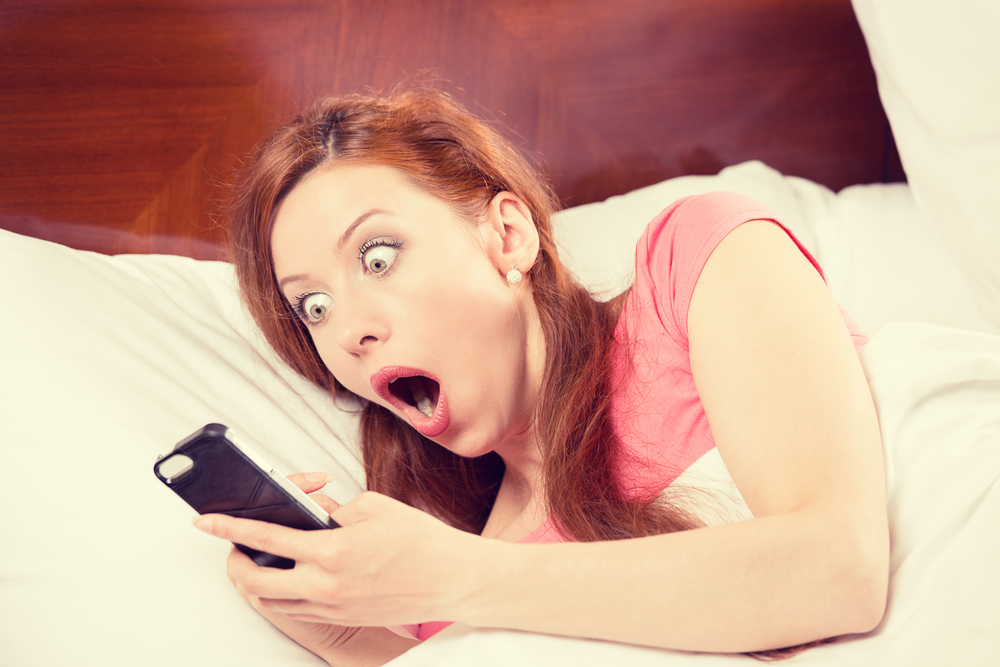 woman looking at her smartphone in shock