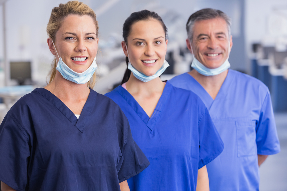 Portrait of smiling co-workers standing in a line in dental clinic - human assets 