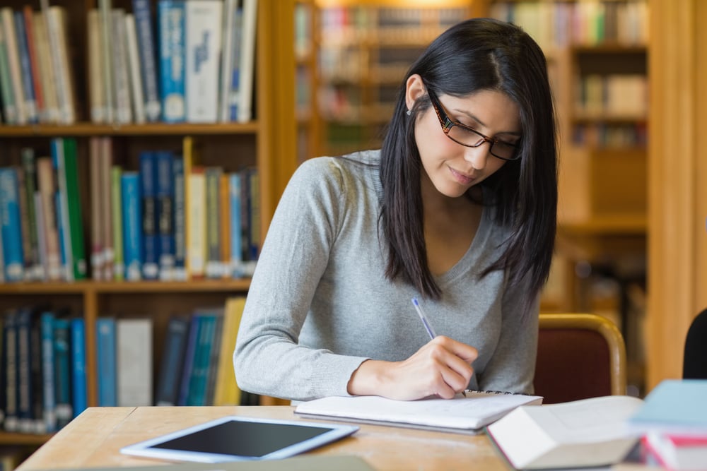 woman writing paper with research sources