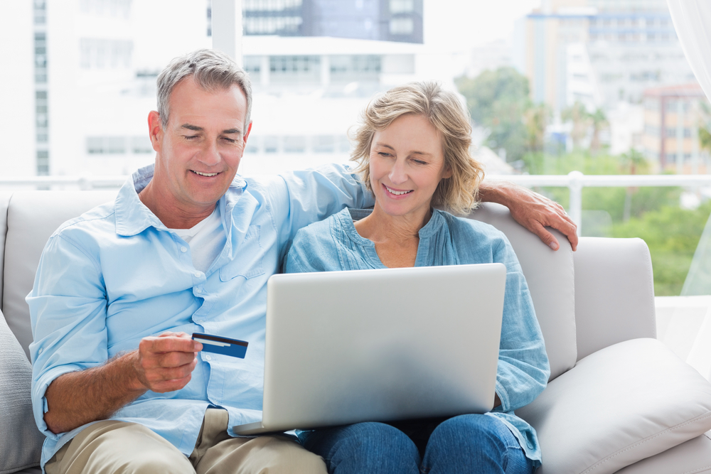 couple sitting looking at their computer and smiling 