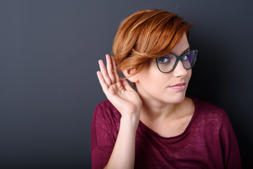 young woman cupping her ear to listen