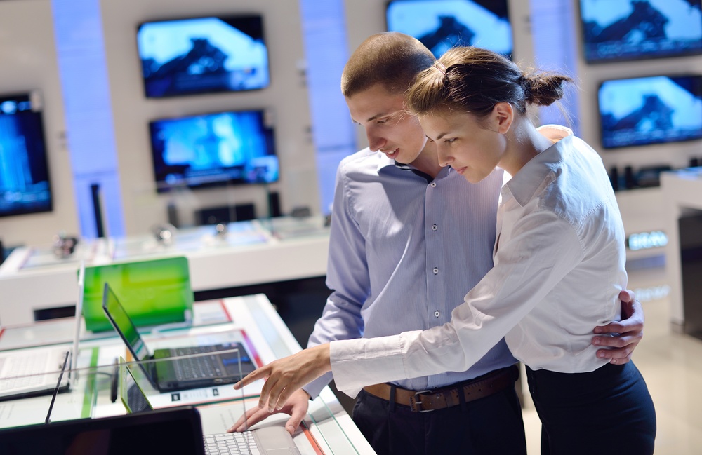 people in consumer electronics  retail store looking at latest laptop, television and photo camera to buy