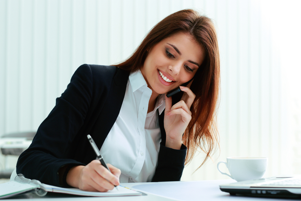 Happy Woman on phone taking notes