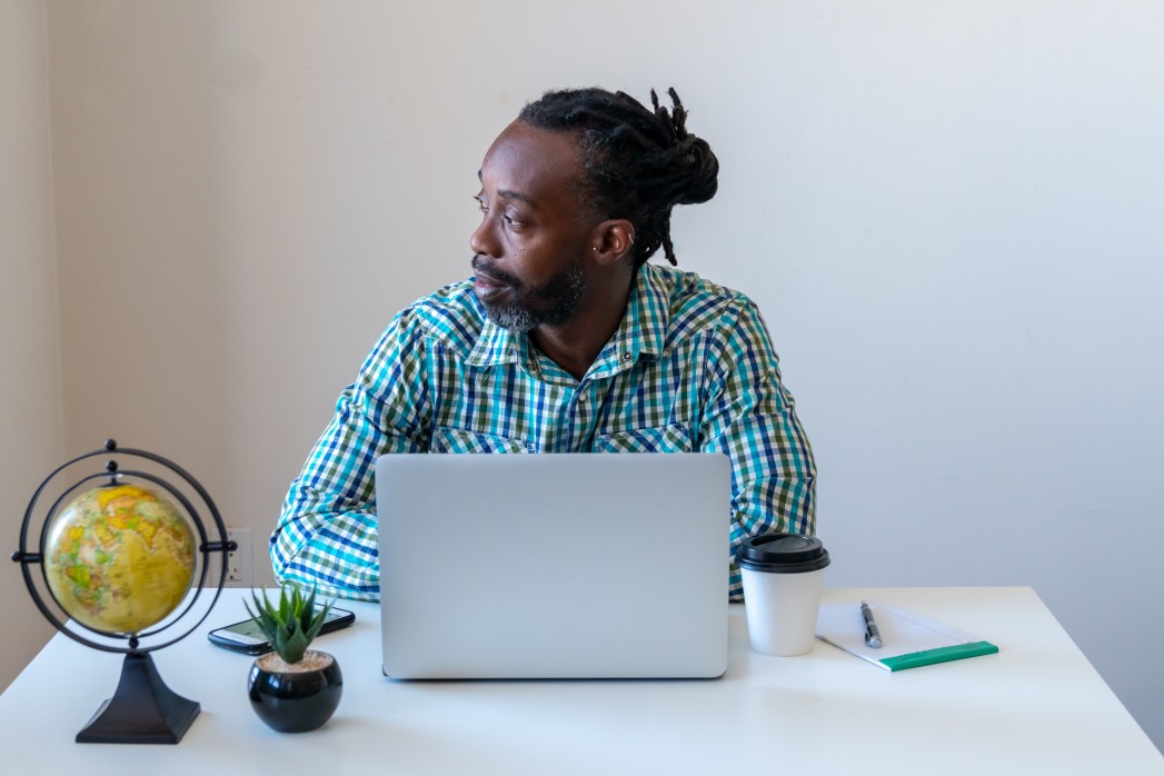 Black man in front of computer staring into space. https://www.twenty20.com/photos/57b4eac3-2aad-4999-85e8-8794a29b0c2f/?utm_t20_channel=bl